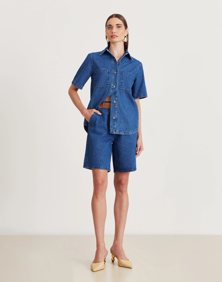 Camisa Bonnie confeccionada em jeans com lavagem escura. Versátil, pode ser usada aberta como sobreposição ou fechada, compondo combinações modernas e despojadas.
