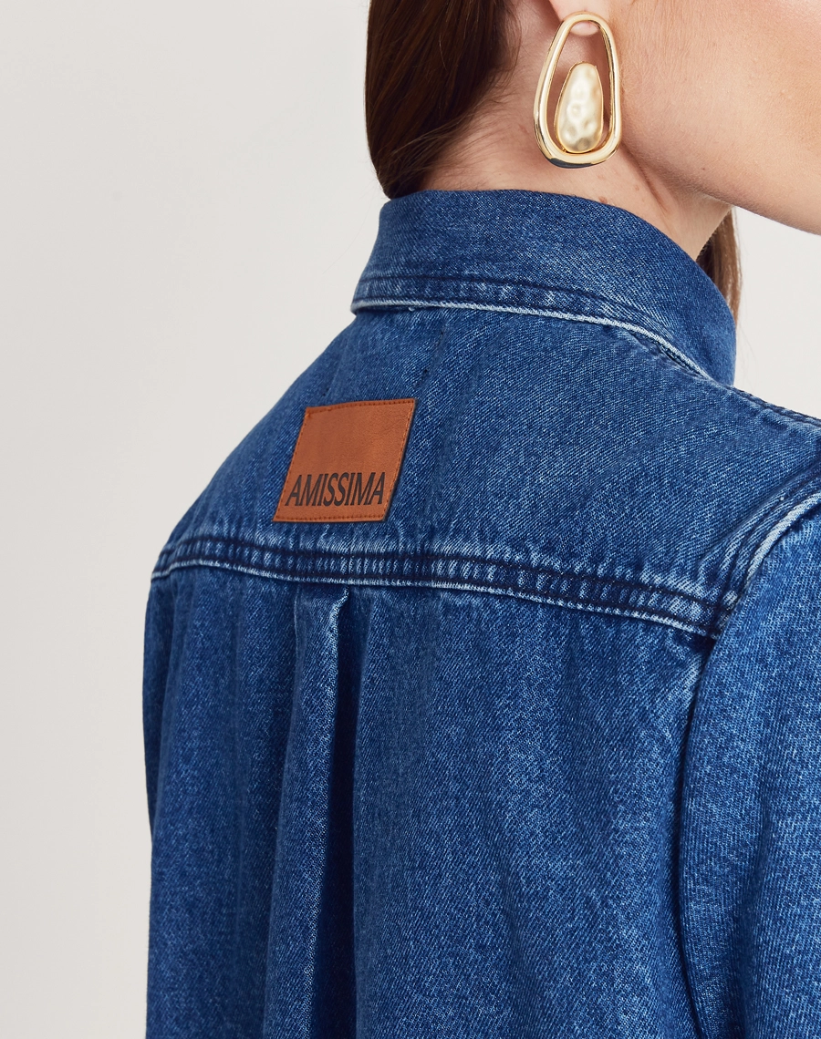 Camisa Bonnie confeccionada em jeans com lavagem escura. Versátil, pode ser usada aberta como sobreposição ou fechada, compondo combinações modernas e despojadas.