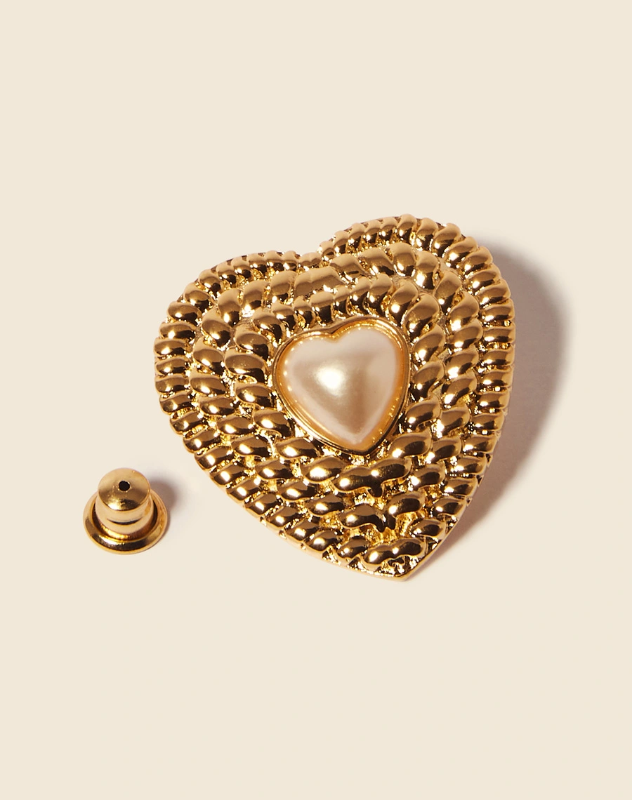 Brincos boucle em forma de coração, delicadamente texturizados e adornados com uma pérola. <br/>
Cada peça é meticulosamente feita à mão e possui um acabamento banhado a ouro. <br/>