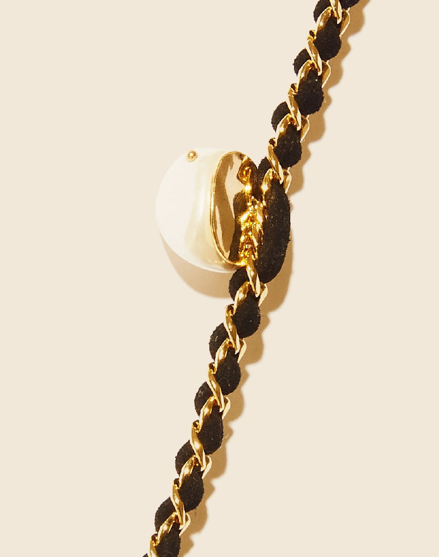 Colar Heart Chain confeccionado manualmente em corrente de elo grumet banhada a ouro com fio de couro e pingente frontal de pérola shell. <br/>
Possui fecho lagosta para regulagem.