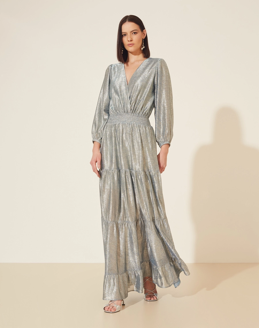 Vestido Longo Desirée confeccionado em Malha Lamê. <br/>
Possui decote V, manga longa bufante e elástico na cintura. <br/>
Vestido acinturado. <br/>