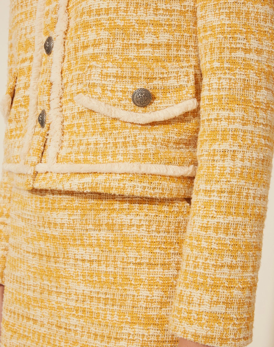 Blazer Blanche em tweed com botões frontais, gola careca com bolsos frontais com lapela decorativa e detalhes felpudos.