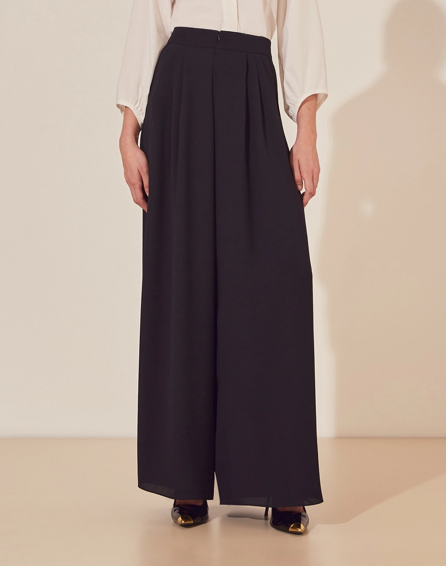 Calça Clarice confeccionada em Crepe Bibi. <br/>
Possui modelagem ampla com caimento leve.<br/>
Possui pregas e seu fechamento é por ziper invísivel na frente.<br/>