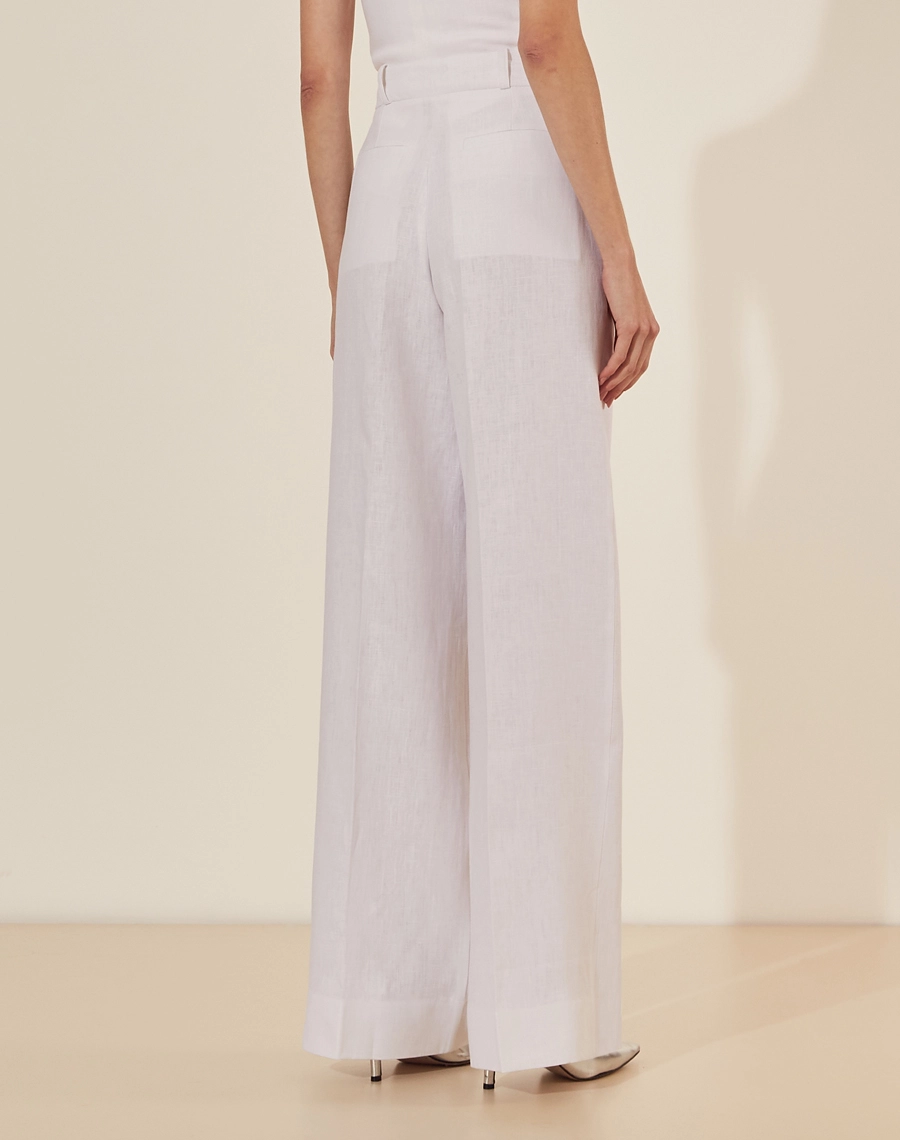 Calça Eugenia, confeccionado em linho, um tecido estruturado com toque rústico. Com modelagem pantalona, bolsos laterais estilo faca e bolsos decorativos atrás.