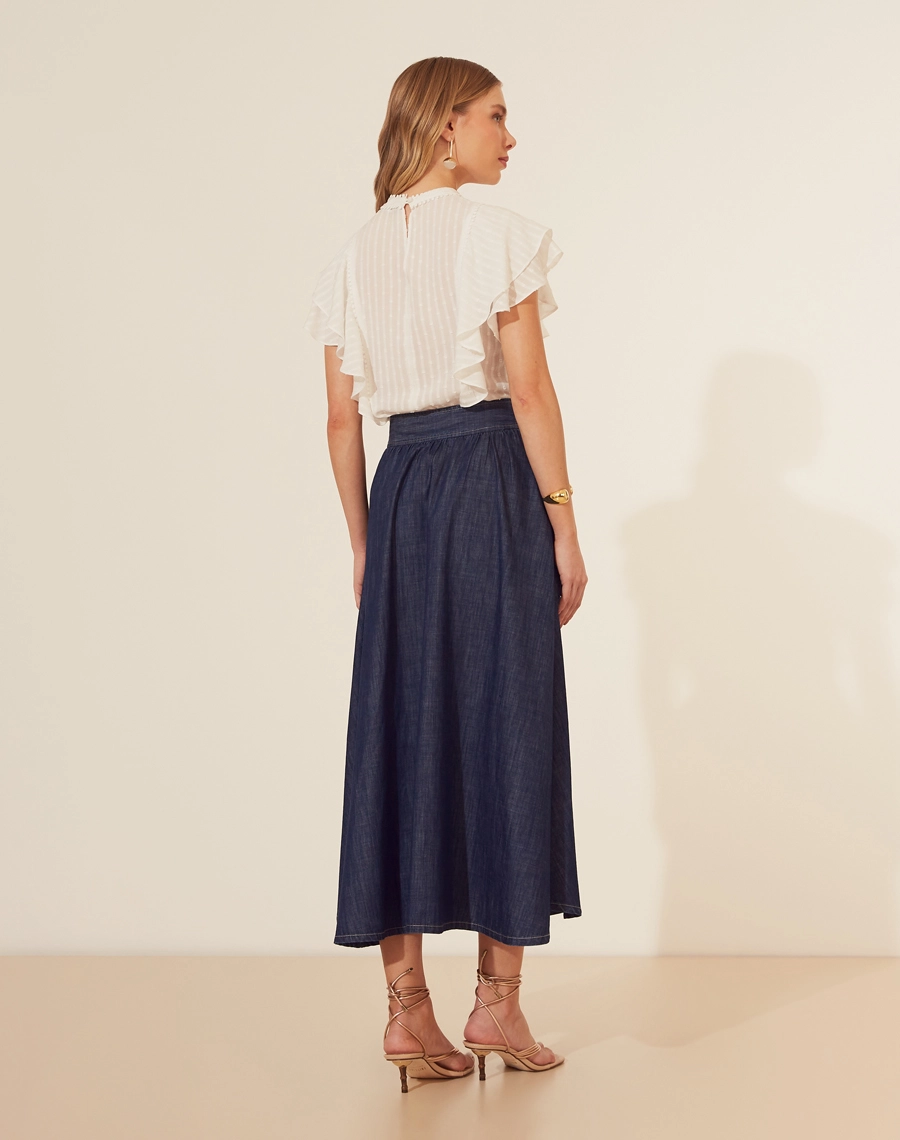 Saia Midi Bonnard confeccionada em Jeans, possui modelagem evasê (ampla), cintura alta e dois bolsos laterais estilo faca. 