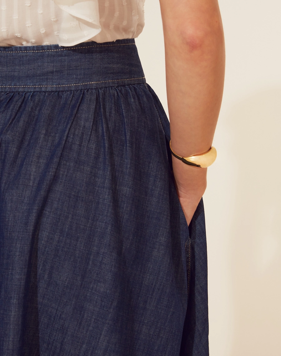 Saia Midi Bonnard confeccionada em Jeans, possui modelagem evasê (ampla), cintura alta e dois bolsos laterais estilo faca. 