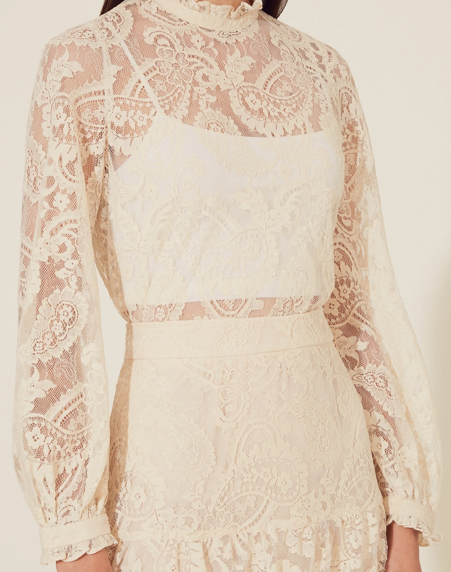 Blusa Belle Epoque é confeccionada em Renda delicada, trazendo uma estética romântica e atemporal. Com mangas longas e gola alta, o modelo é perfeito para compor looks elegantes e sofisticados.