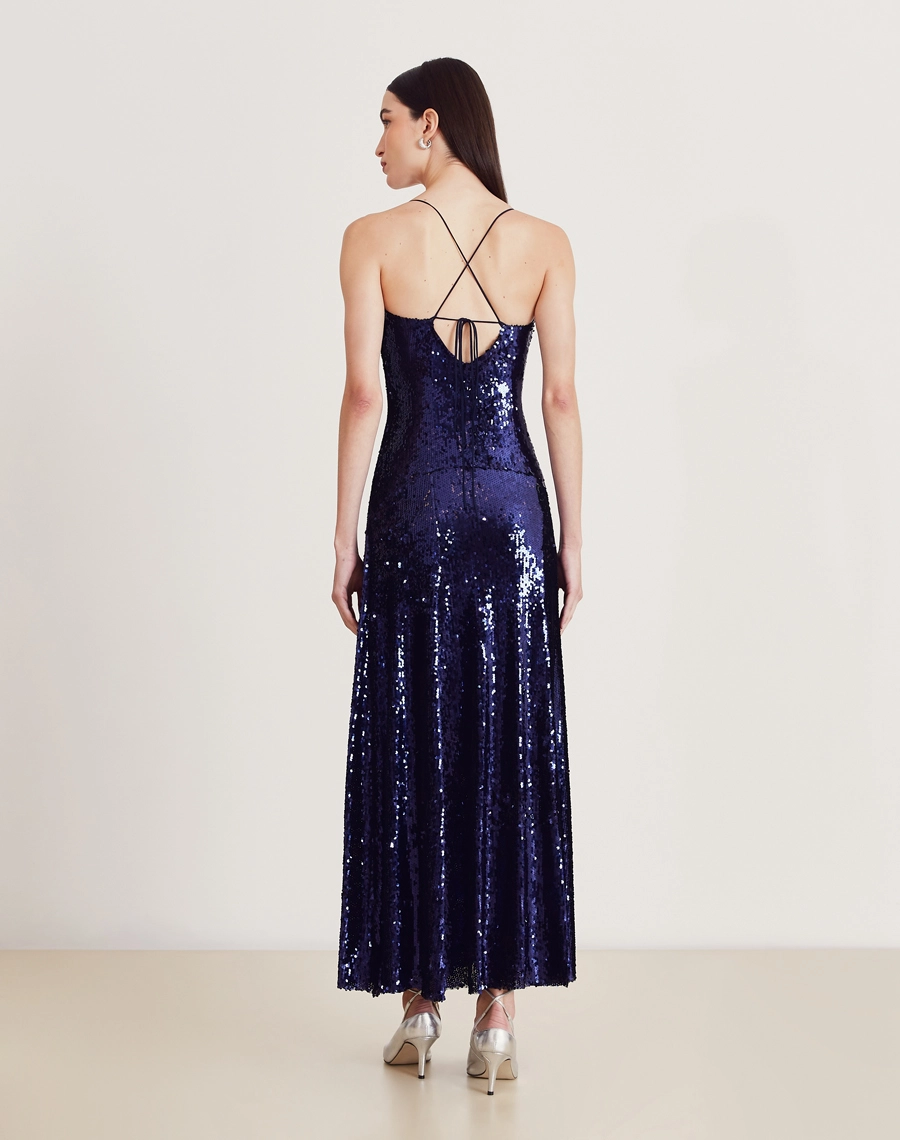 Vestido longo de paetê com alças cruzadas, decote em V e caimento fluido. Glamour e conforto para festas e eventos sofisticados.