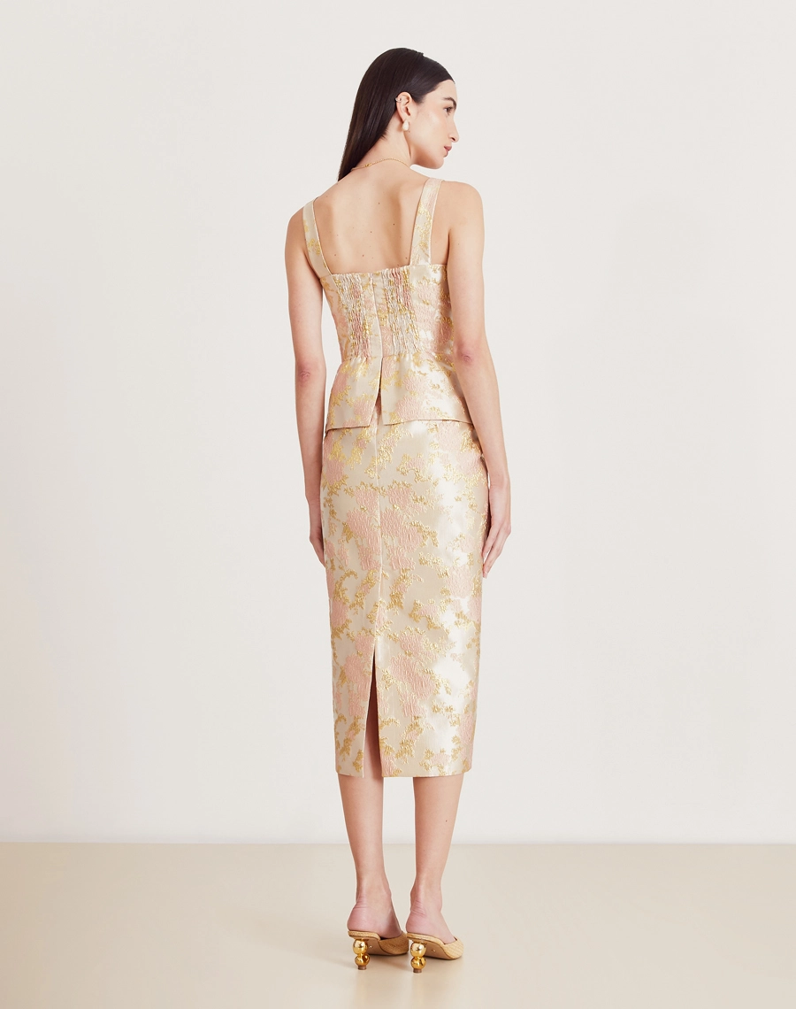 Vestido midi em jacquard com folhas douradas, decote coração, peplum e fenda traseira. Elegante e confortável para eventos especiais.


