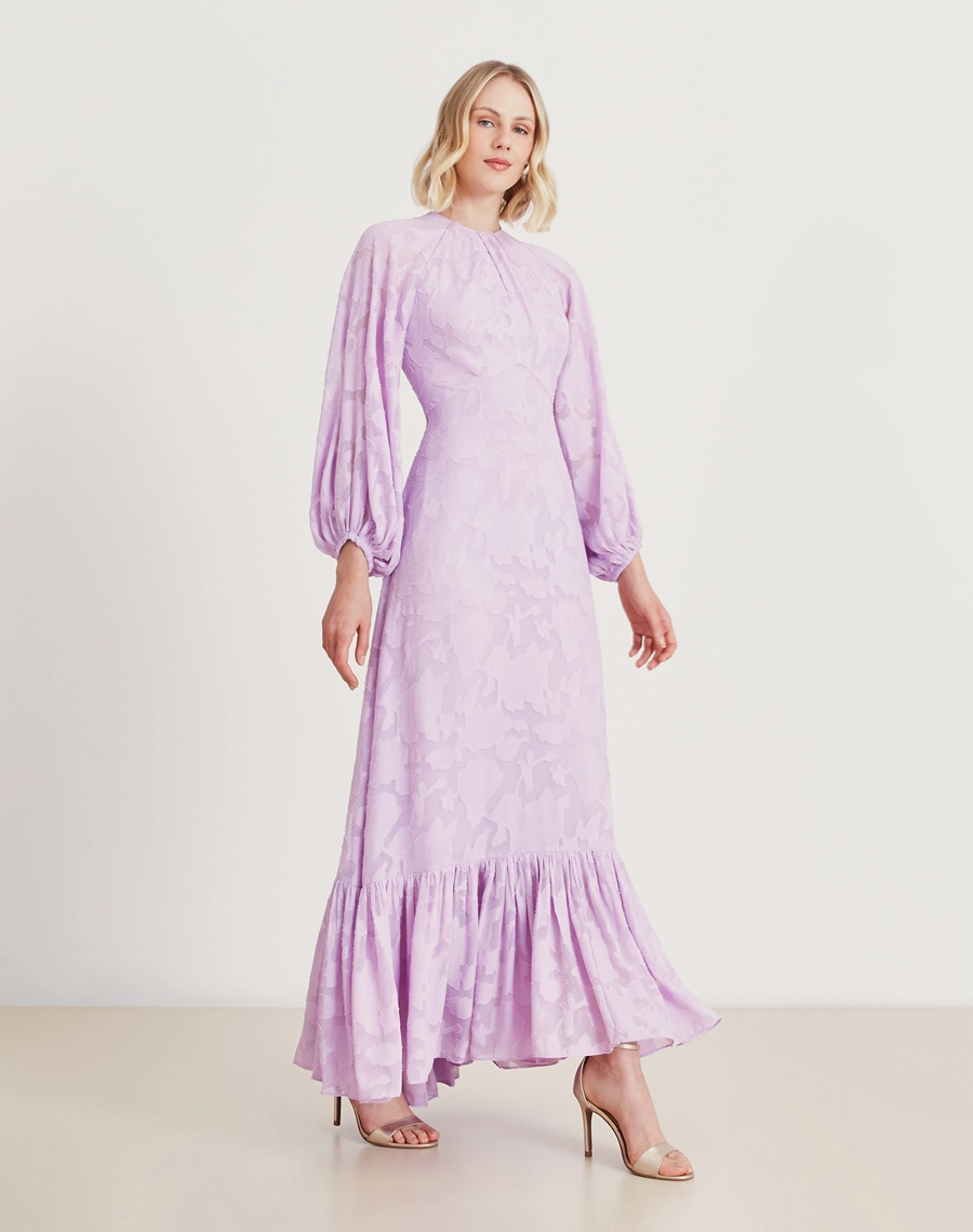 Vestido longo lavanda em jacquard floral com mangas bufantes e babado na barra. Sofisticação e elegância para eventos especiais.