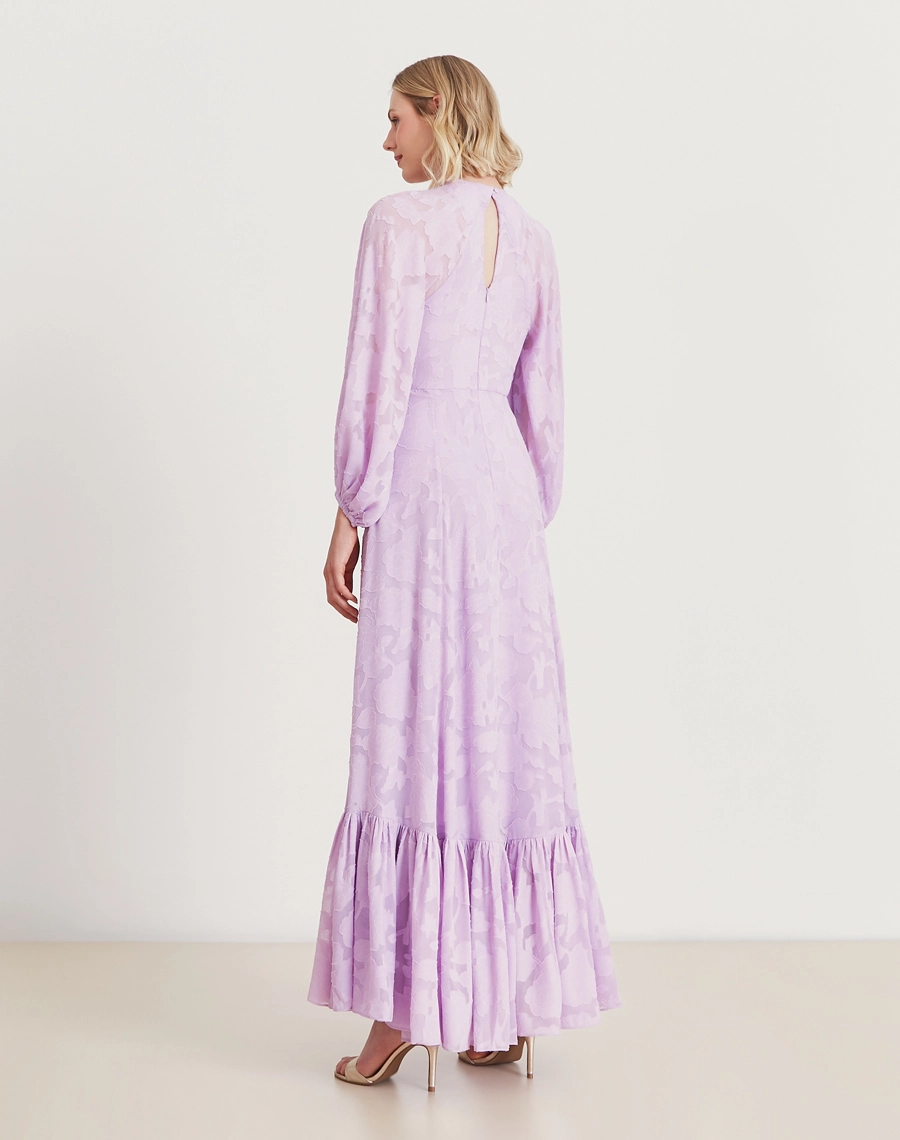 Vestido longo lavanda em jacquard floral com mangas bufantes e babado na barra. Sofisticação e elegância para eventos especiais.