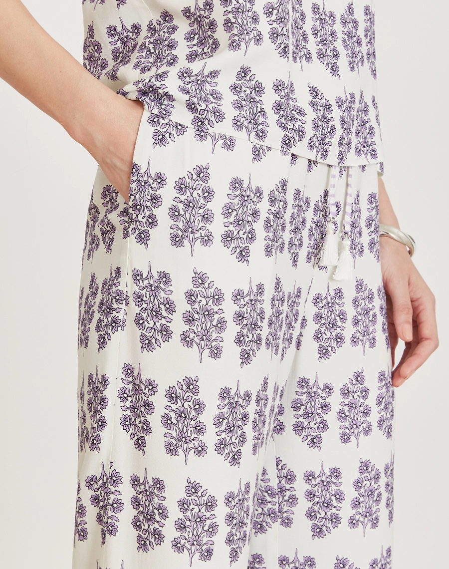 A Calça Lylla é confeccionada em viscose estampada, um tecido leve e suave ao toque, oferecendo leveza e frescor ao vestir. Com estampa floral Amissima exclusiva em tons de roxo sobre fundo claro. 