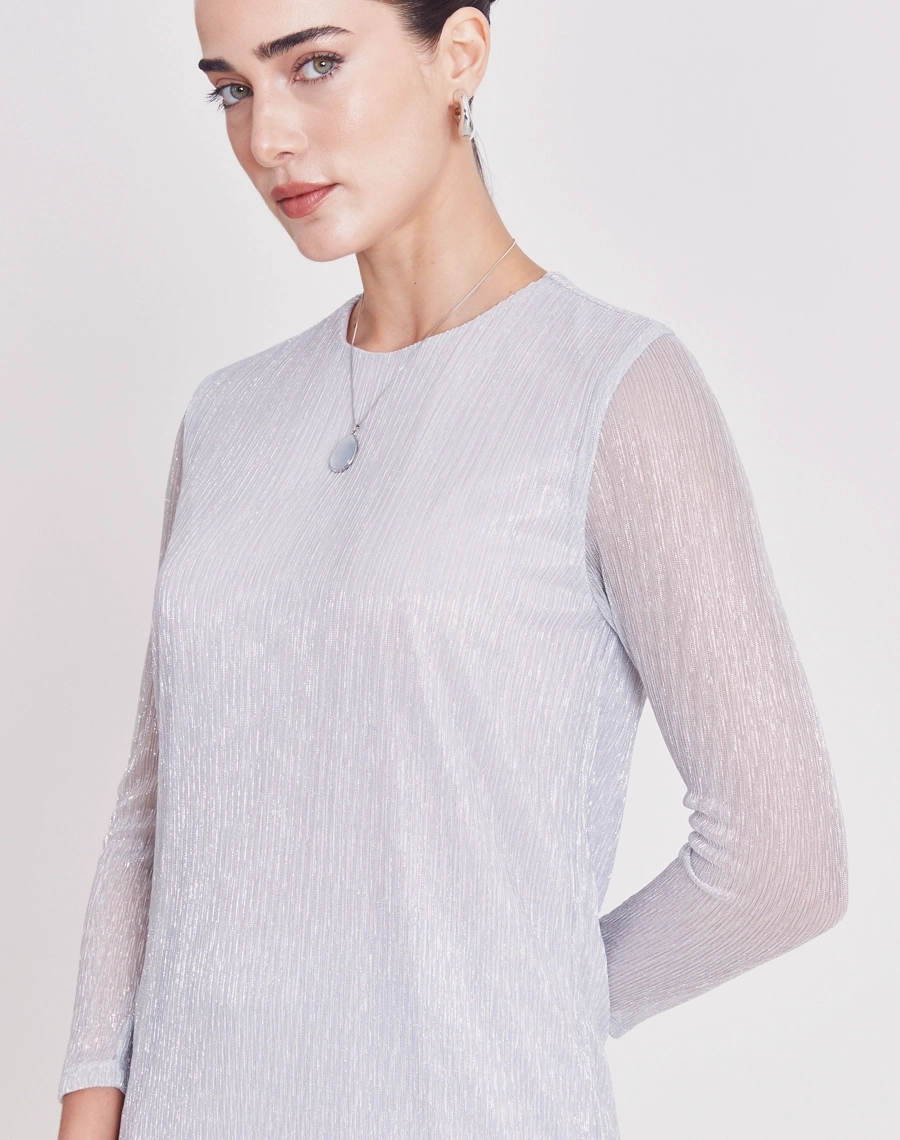 A Blusa Liliana é confeccionada em malha plissada, tecido leve e confortável, caracterizado por sua textura elegante e cheia de movimento.