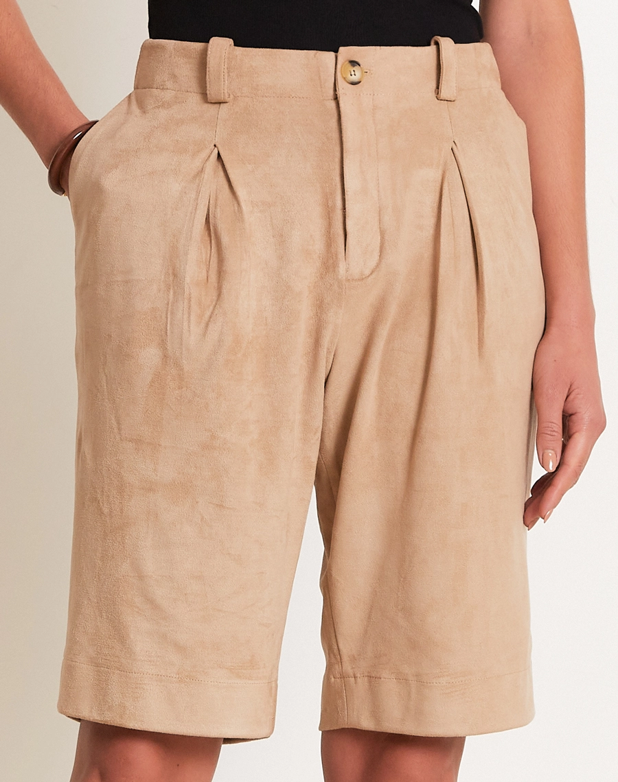 A Bermuda Elora é confeccionada em suede, um tecido conhecido pelo toque macio e acabamento levemente aveludado que remete à camurça.