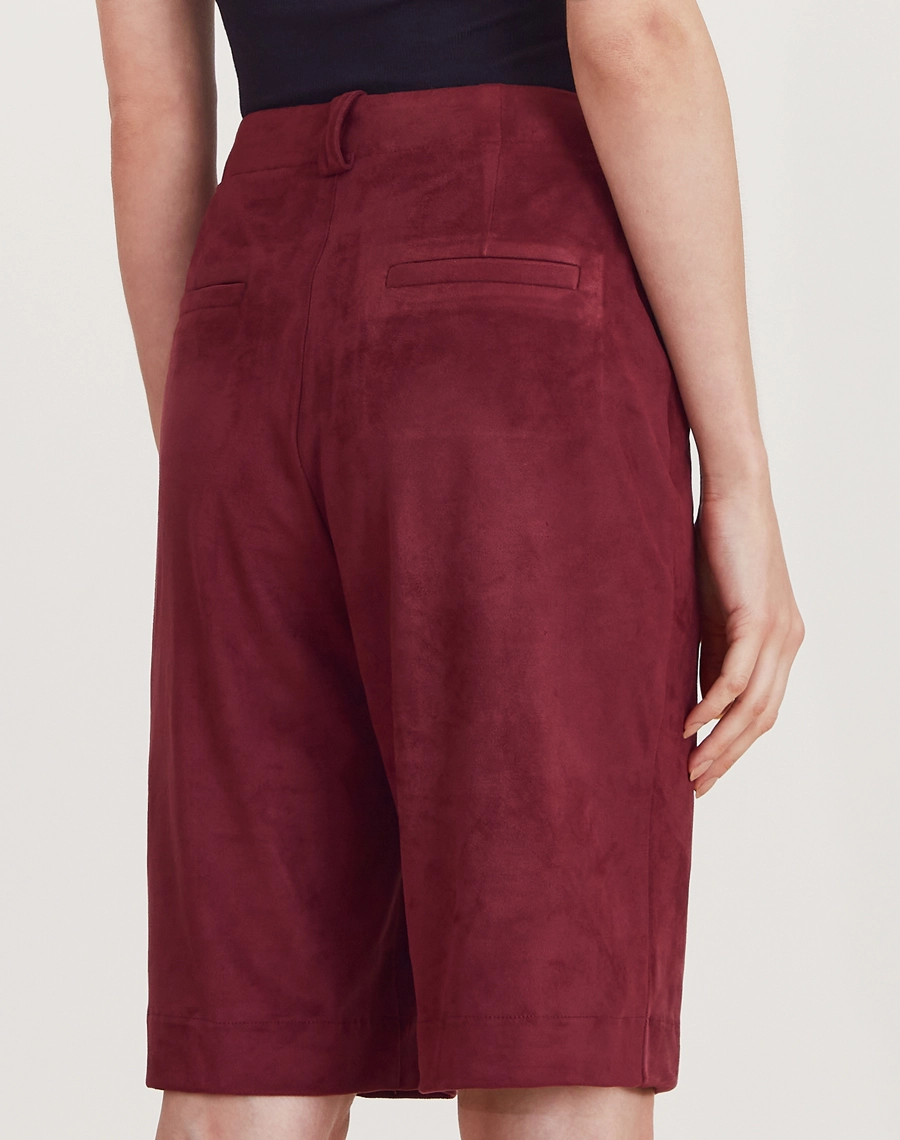 A Bermuda Elora é confeccionada em suede, um tecido conhecido pelo toque macio e acabamento levemente aveludado que remete à camurça.