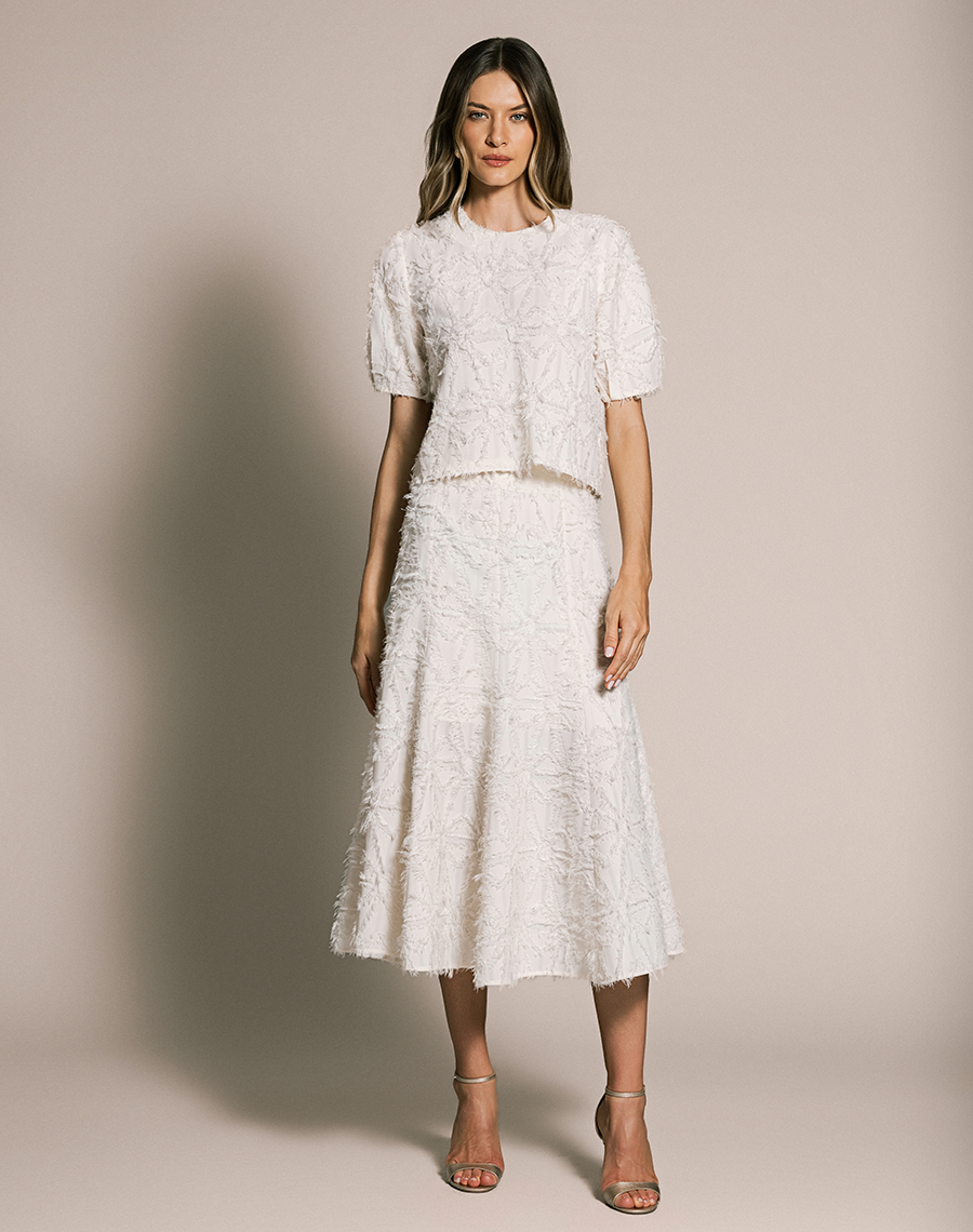 A Saia Midi Talia confeccionada em Jacquard, tecido de alto padrão, com desenho em relevo e textura levemente desfiada que adiciona sofisticação e um toque moderno à peça.