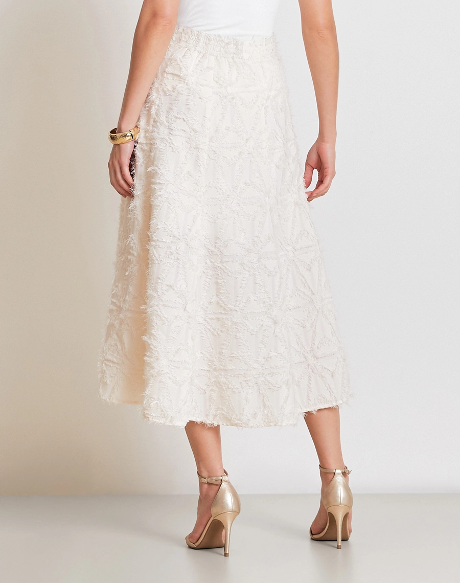 A Saia Midi Talia confeccionada em Jacquard, tecido de alto padrão, com desenho em relevo e textura levemente desfiada que adiciona sofisticação e um toque moderno à peça.