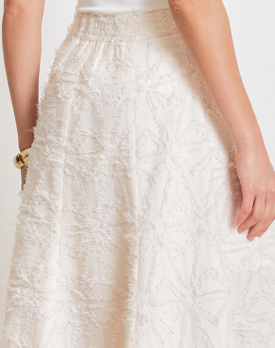 A Saia Midi Talia confeccionada em Jacquard, tecido de alto padrão, com desenho em relevo e textura levemente desfiada que adiciona sofisticação e um toque moderno à peça.
