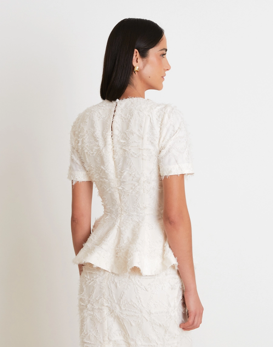 A Blusa Clarisse confeccionada em Tecido Jacquard Diagonal com textura rica e sofisticada, destacando desenhos em relevo que trazem profundidade e um visual refinado à peça.