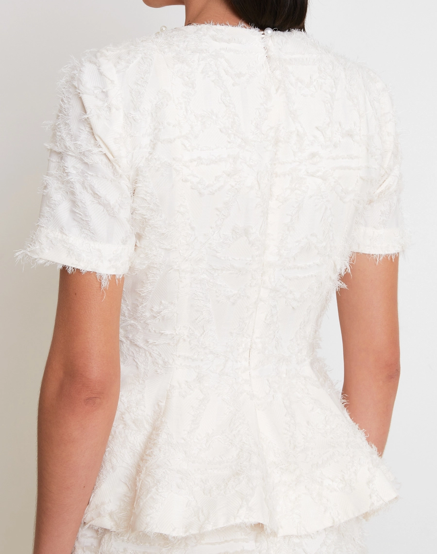A Blusa Clarisse confeccionada em Tecido Jacquard Diagonal com textura rica e sofisticada, destacando desenhos em relevo que trazem profundidade e um visual refinado à peça.