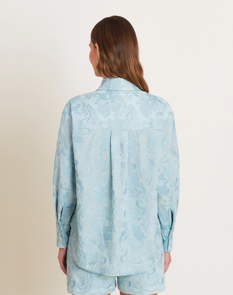 A Camisa Arabela é confeccionada em algodão bordado, com textura delicada e padronagem floral que traz charme ao visual.