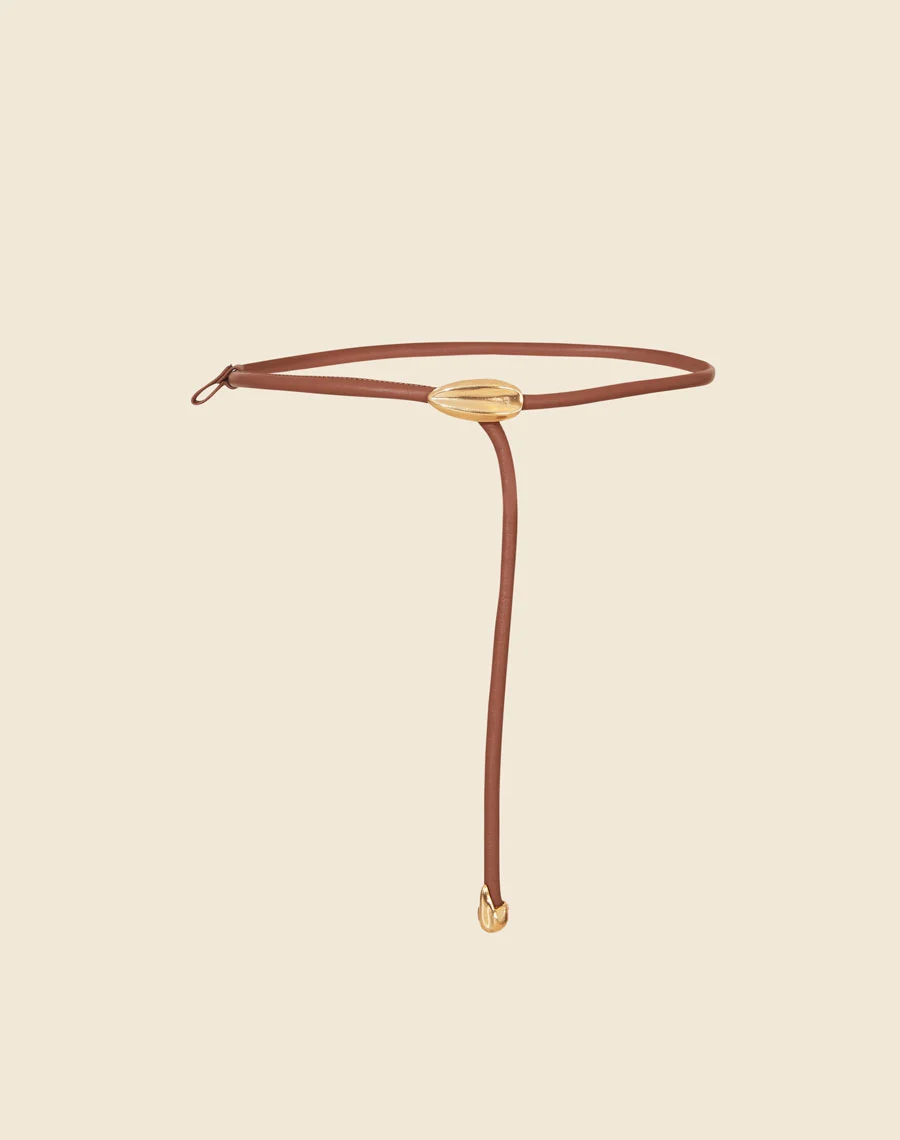 Cinto Anyka é uma peça sofisticada e minimalista, confeccionada em couro de alta qualidade. <br/>
Com um design fino e detalhe central em metal dourado, ele adiciona um toque de modernidade e elegância a qualquer look. <br/>
Ideal para complementar vestidos, saias e calças de cintura alta, este cinto ajustável garante um caimento perfeito, valorizando a silhueta com sutileza. <br/>