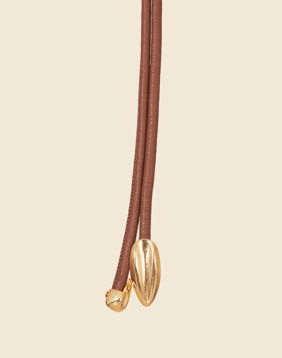 Cinto Anyka é uma peça sofisticada e minimalista, confeccionada em couro de alta qualidade. <br/>
Com um design fino e detalhe central em metal dourado, ele adiciona um toque de modernidade e elegância a qualquer look. <br/>
Ideal para complementar vestidos, saias e calças de cintura alta, este cinto ajustável garante um caimento perfeito, valorizando a silhueta com sutileza. <br/>