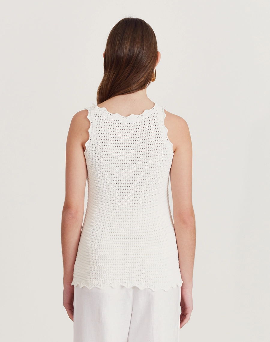 Regata de tricot feminina com babados e detalhes vazados. Toque macio e visual delicado, perfeita para dias amenos e looks elegantes.