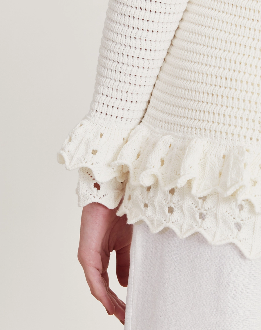 Casaquinho feminino em tricot com babados e gola esportiva. Toque macio, visual sofisticado e ideal para dias frescos e ocasiões casuais.